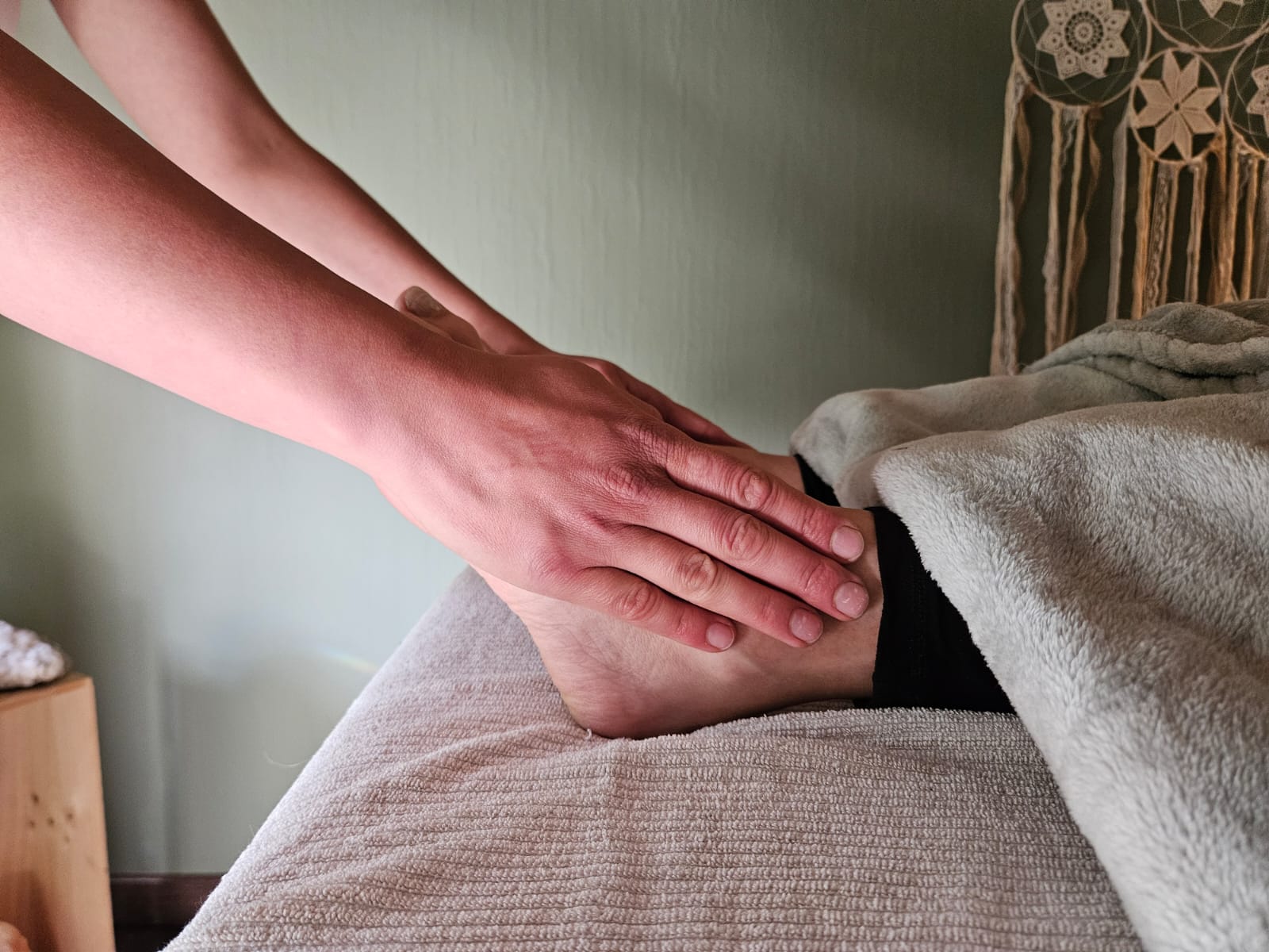 Mains posées délicatement sur un pied lors d'un soin par acupression